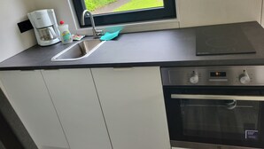 Een moderne keuken met een ingebouwde vaatwasser, een koffiezetapparaat en een raam met uitzicht op een tuin.