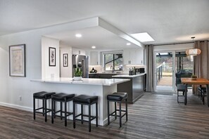 A modern kitchen with a central island, bar stools, and a dining area with a table and chairs. - Escape to Manor Hill Haven! Accessible 2BR retreat with hot tub, modern comfort & mountain views. Perfect for families, couples & business travelers. (Medford)