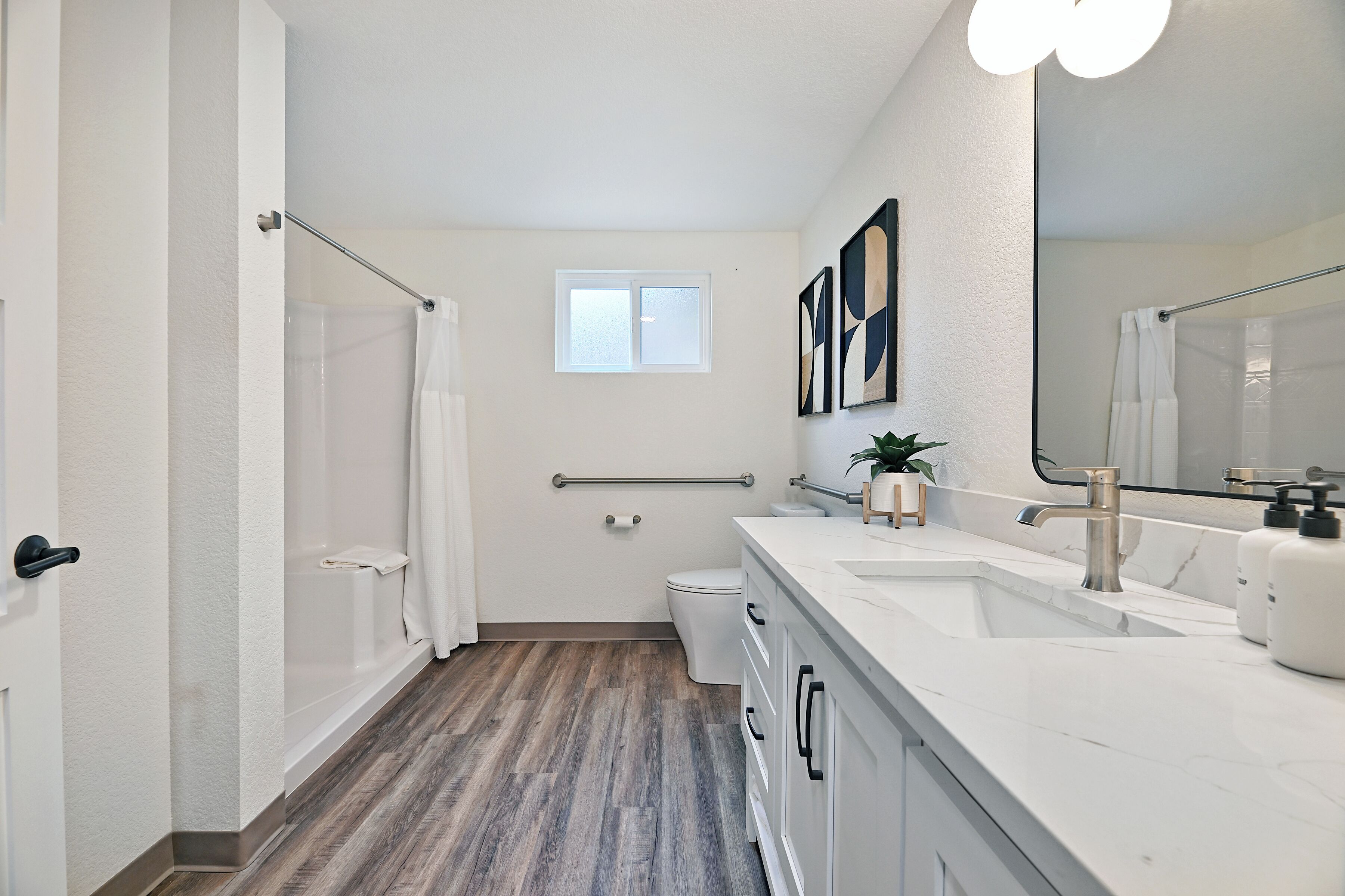 Een moderne badkamer met douche, toilet en wastafel.