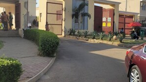 A gated entrance with a clear driveway leading to a building with a modern design.
