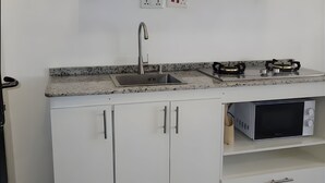 A kitchen with white cabinets, a stainless steel sink, a gas stove, and a microwave.