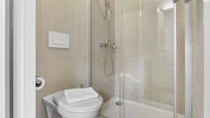 A bathroom with a toilet, a shower, and a glass-enclosed shower stall.