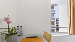 A hotel room with a single bed, a window with a view of a building, a potted orchid, and two water bottles on the nightstand. - Cosy twin room in the heart of Sierre (Sierre)