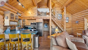 Ein Holzblockhaus-Interieur mit Küche, Essbereich und Wohnzimmer.