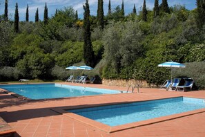 Una piscina al aire libre de temporada, sombrillas, tumbonas