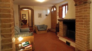 A cozy living room with a fireplace, a sofa, and a coffee table. - Comiti Farmhouse - David Apartment (Montaione)