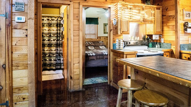 A cabin interior with a kitchen, a bathroom, and a sleeping area. - Golden Trout-2 bedroom/Hot Tub/Location (Broken Bow)