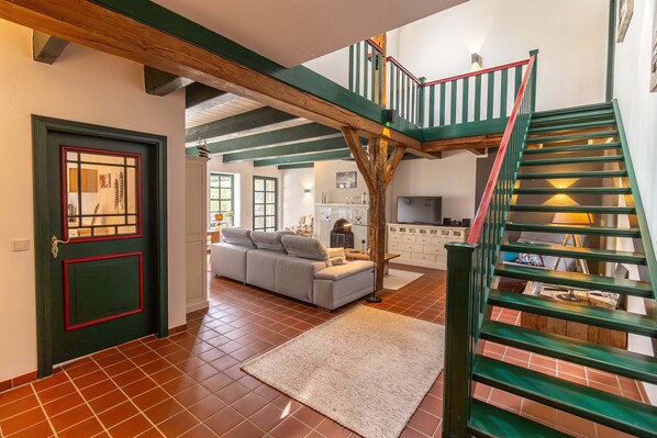 A spacious living area with a staircase, a sofa, and a kitchen in the background.