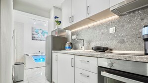 A modern kitchen with white cabinets, a built-in oven, a coffee machine, and a kettle. - Premium Jacuzzi Suite at the City Center (Thessaloniki)