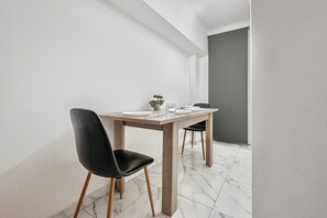 Un comedor minimalista con una mesa de madera, sillas negras y una pequeña planta en maceta.
