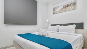 A neatly made bed with white linens and a blue accent, a headboard, and a wall-mounted light fixture. - Premium Jacuzzi Suite at the City Center (Thessaloniki)