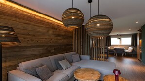 A modern living room with a sectional sofa, round wooden coffee table, and hanging pendant lights.