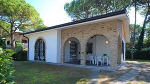 Una casa moderna con un porche cubierto, paredes de ladrillo arqueadas y una pequeña zona de estar al aire libre con mesas y sillas.