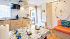 Una cucina con TV, un tavolo da pranzo con tazze e un boccale, e un decoro a rete sulla parete.