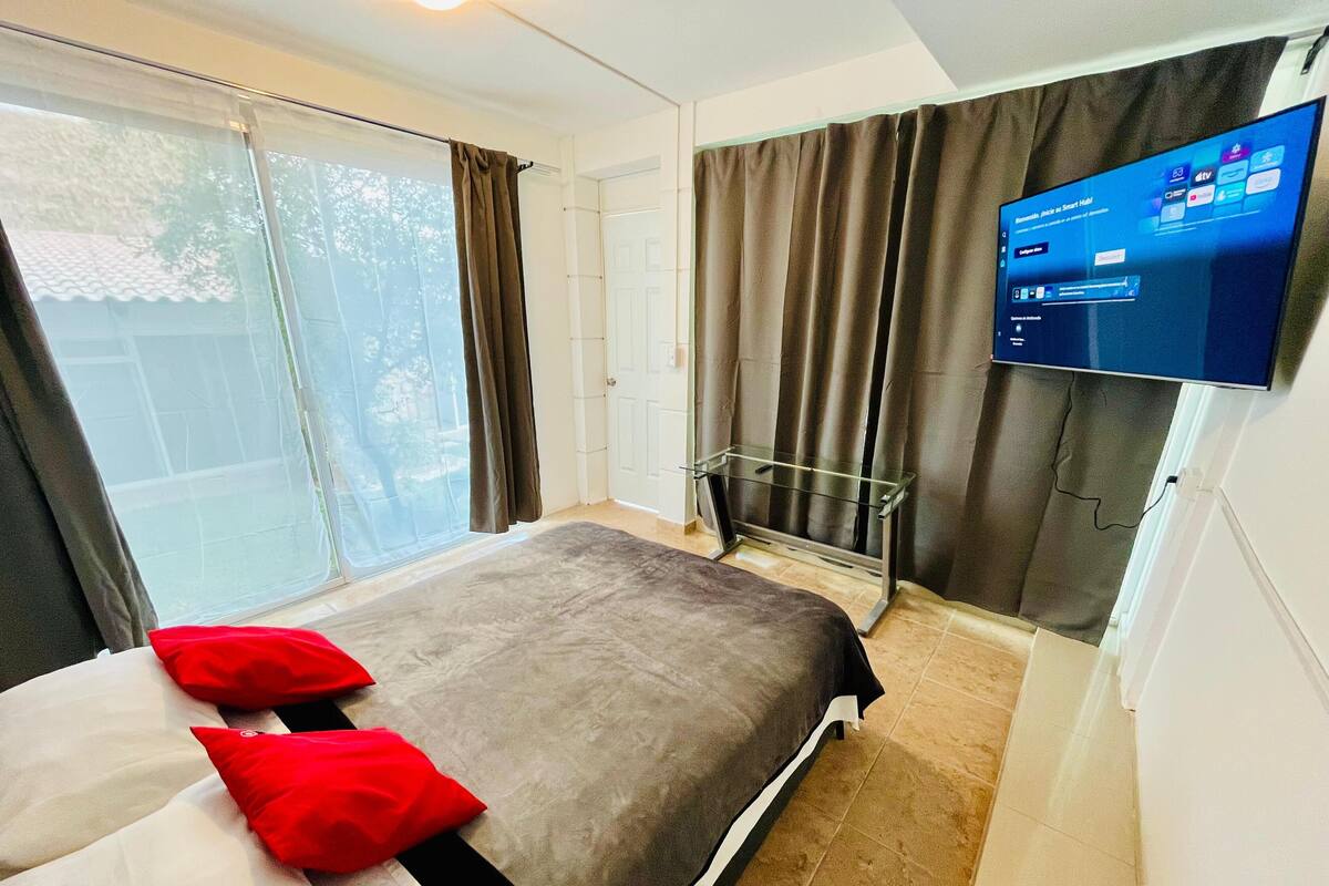 A hotel room with a bed, a TV, and a sliding glass door.