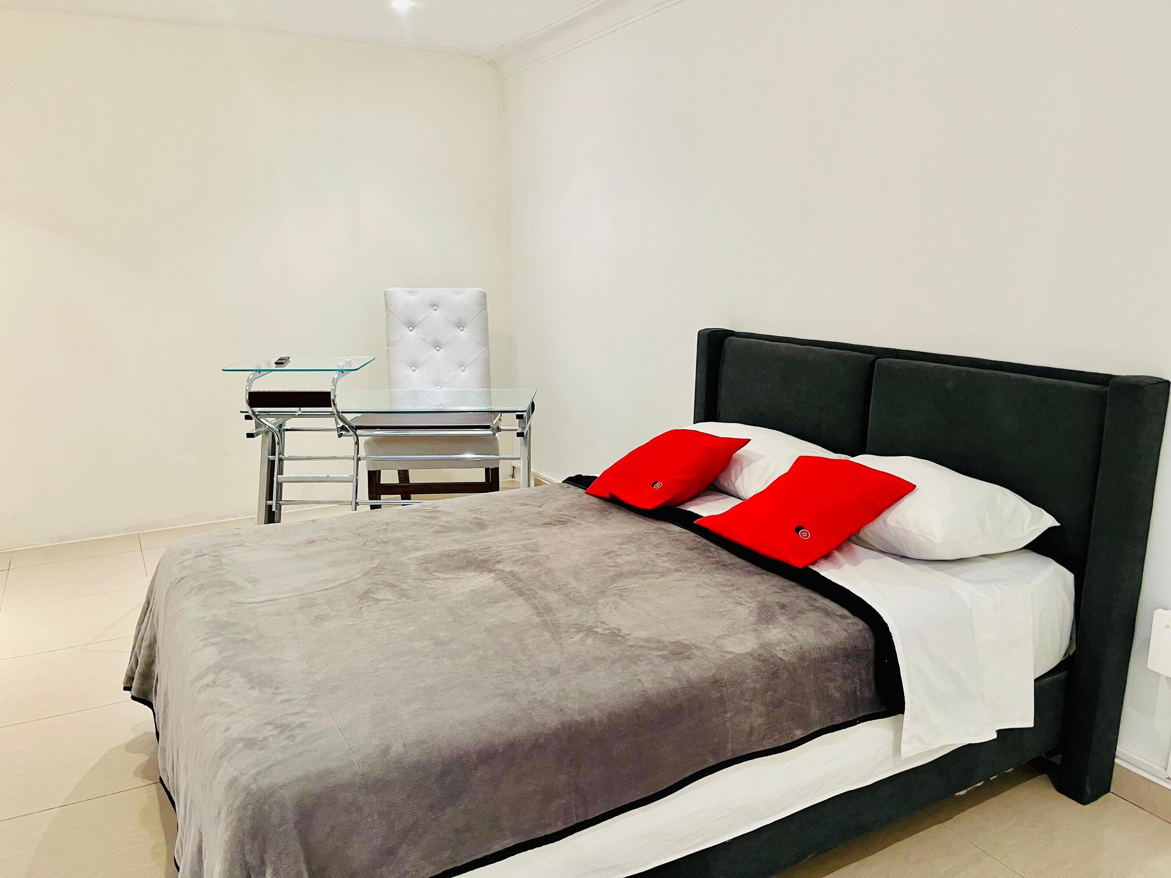 A neatly arranged bedroom with a bed, a bedside table, and a chair.