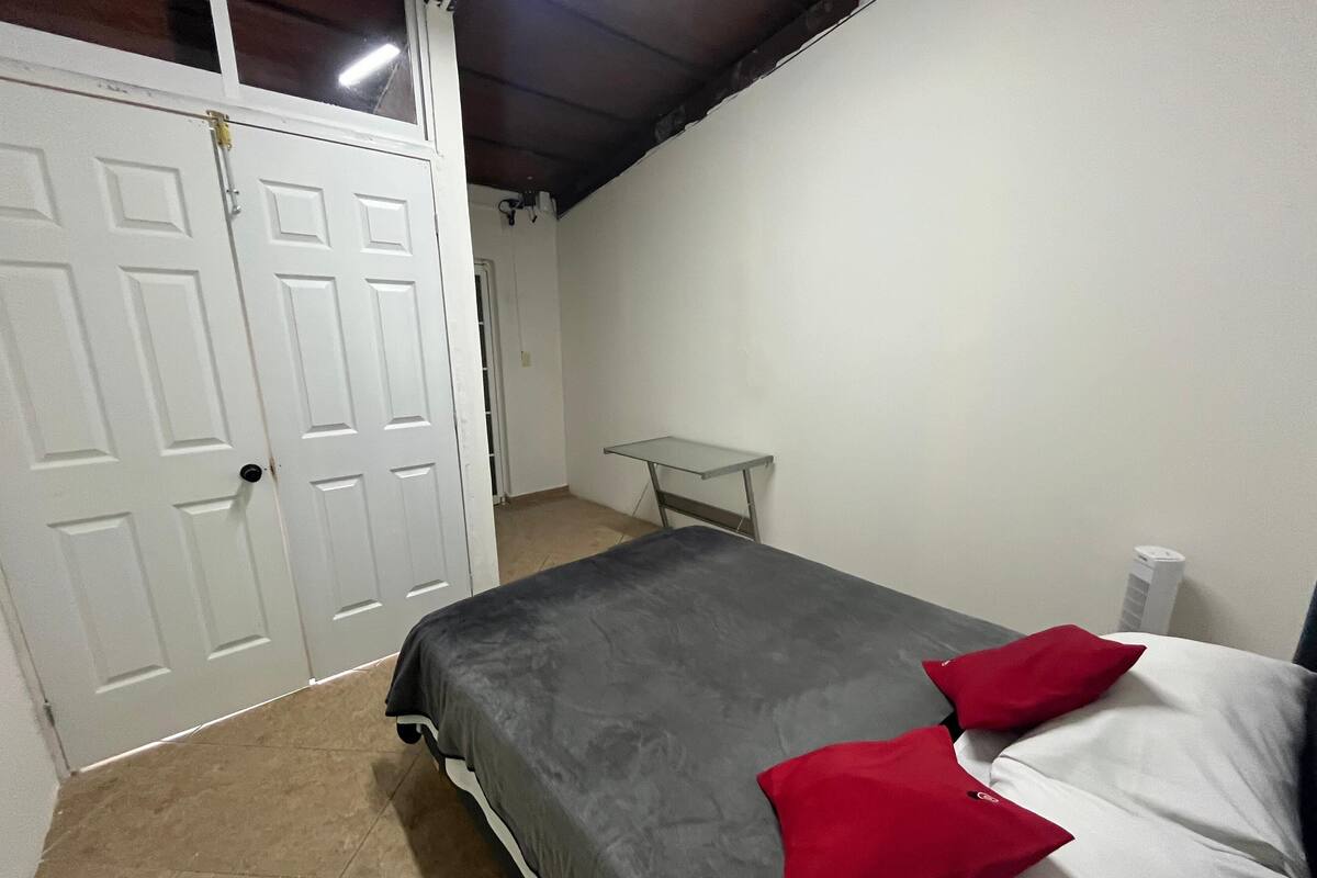 A bedroom with a bed, a desk, and a white door.