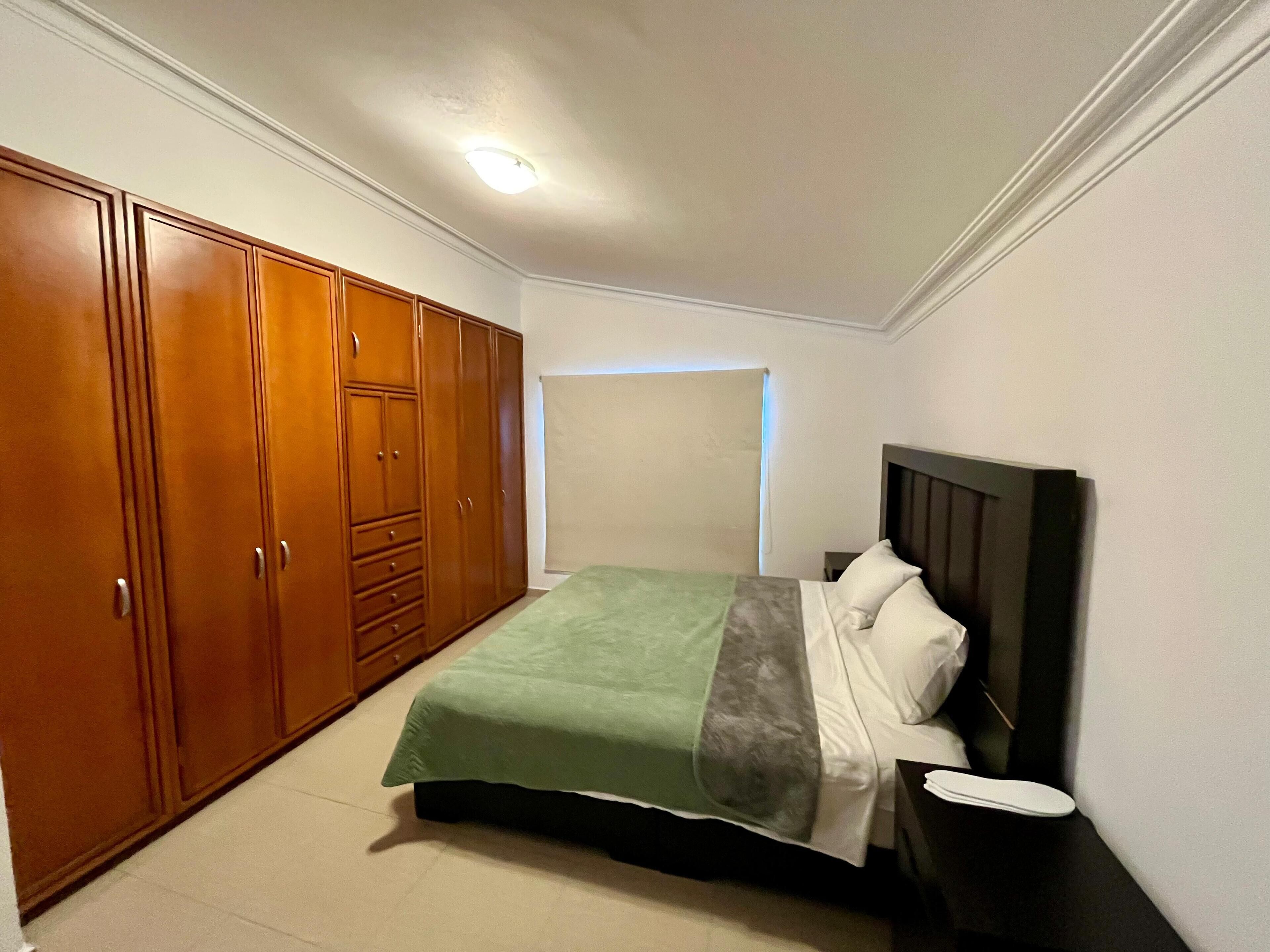 Een slaapkamer met een bed, nachtkastje en een kledingkast.