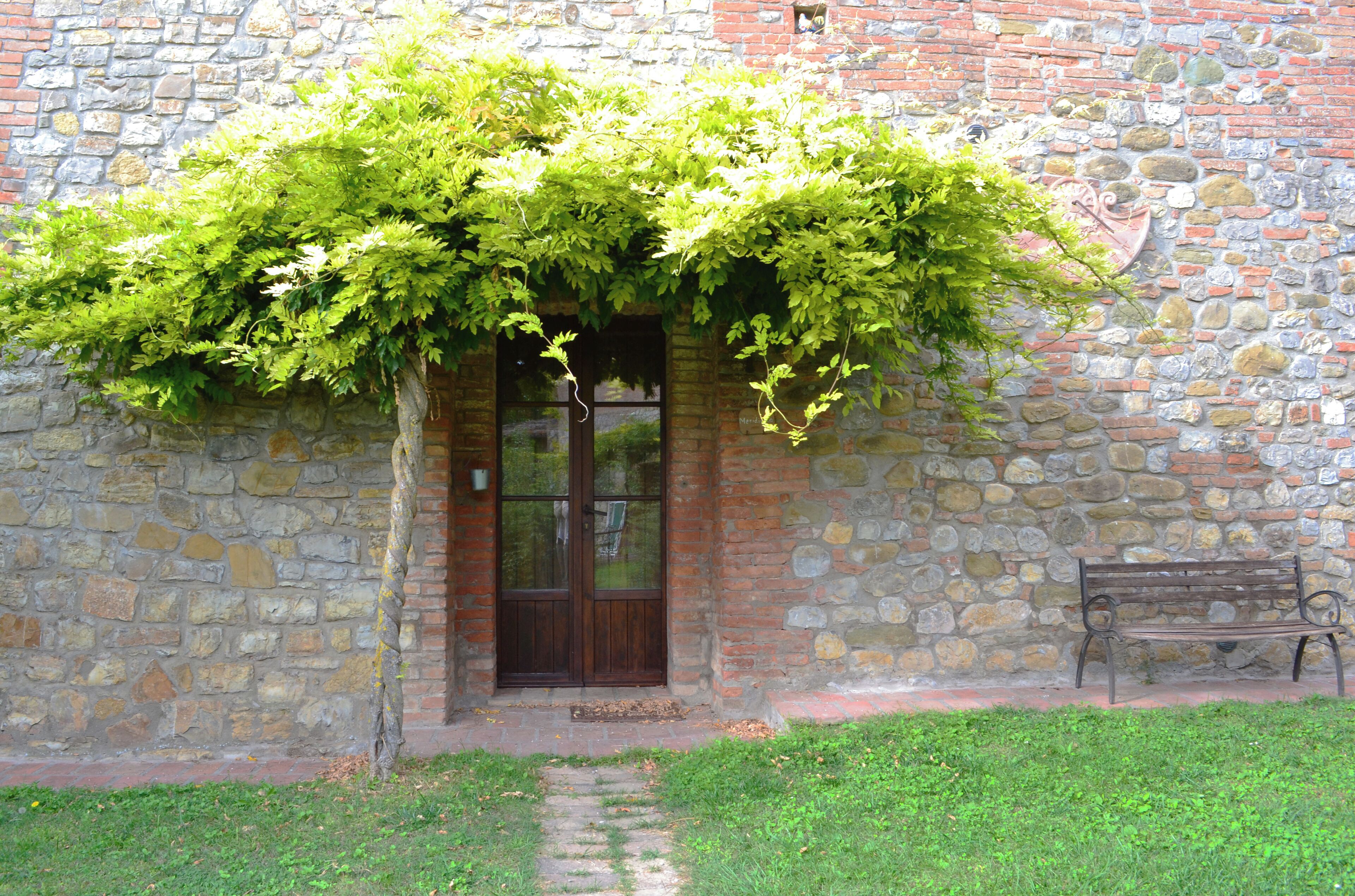 Un bâtiment en pierre avec une porte en bois et un banc à l’extérieur.