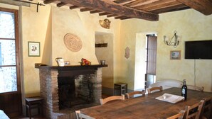 Un coin repas rustique avec une cheminée en pierre, une table en bois et des chaises.