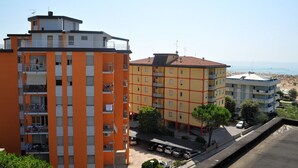 A multi-story building with balconies, a parking area, and a view of the sea. - Spacious apartment 30mt from the beach (Bibione)