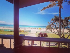 Vista a la playa desde un espacio cubierto, con una palmera y un tractor estacionado.