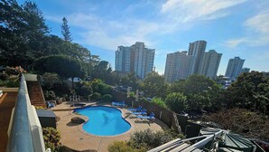 A swimming pool with lounge chairs and a view of tall residential buildings. - Bask in Beach Luxury! (Coolangatta)