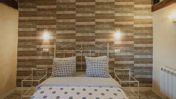 A bedroom with a bed, two bedside tables, a radiator, and a wall with a wooden panel design.