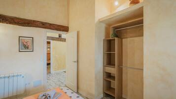 A room with a bed, a wooden wardrobe, a radiator, and a door leading to another room.