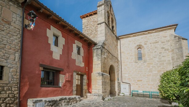 Een gebouw van steen met een rode gevel en een toren, een stenen muur en een geplaveid binnenterrein.