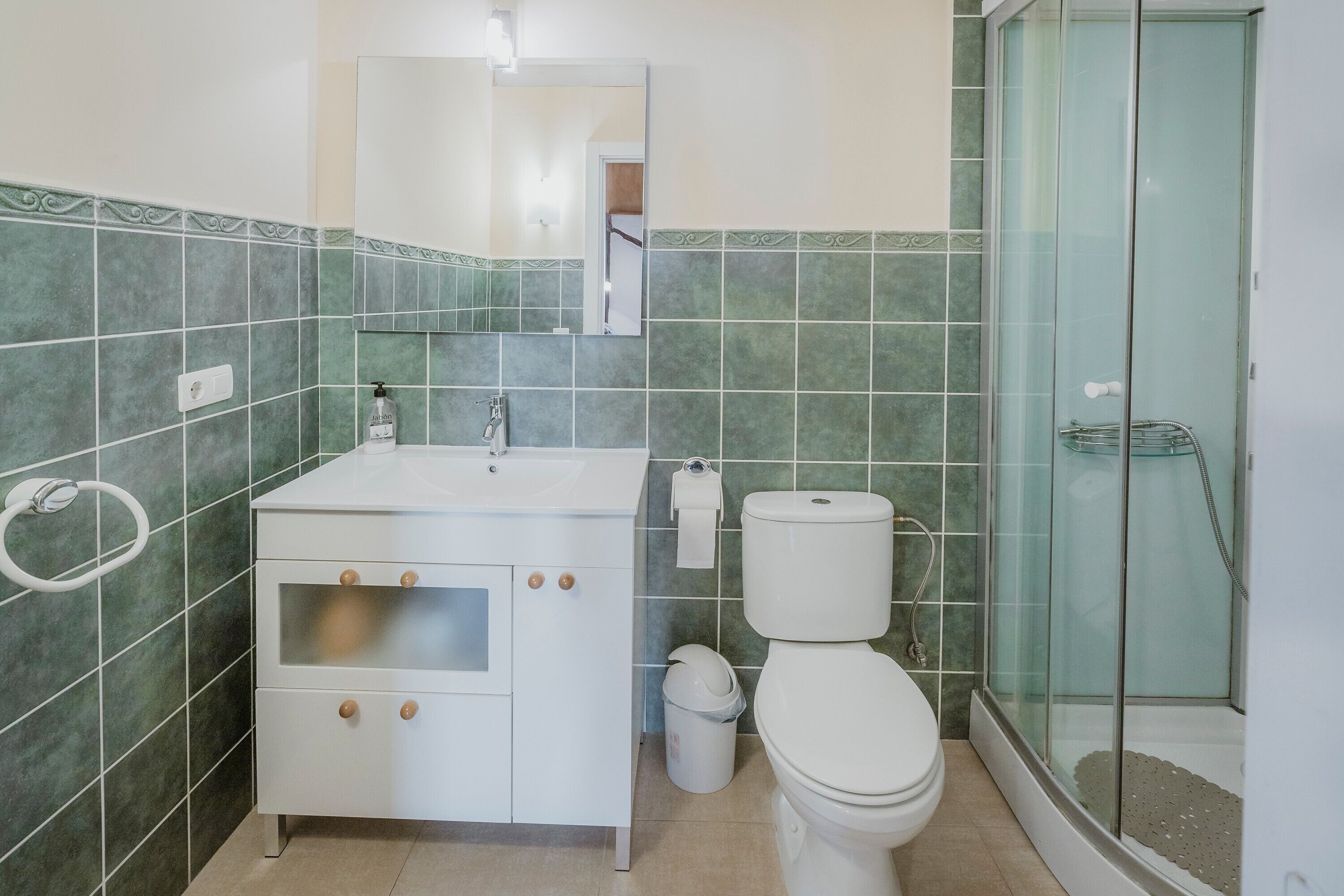 Une salle de bain avec un lavabo, des toilettes et une douche, le tout de couleur blanche.