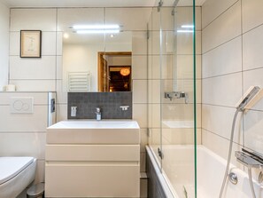 A modern bathroom with a glass shower enclosure, a white sink, and a toilet. - Charming apartment in the heart of Val-d'Isère (Val-d'Isère)