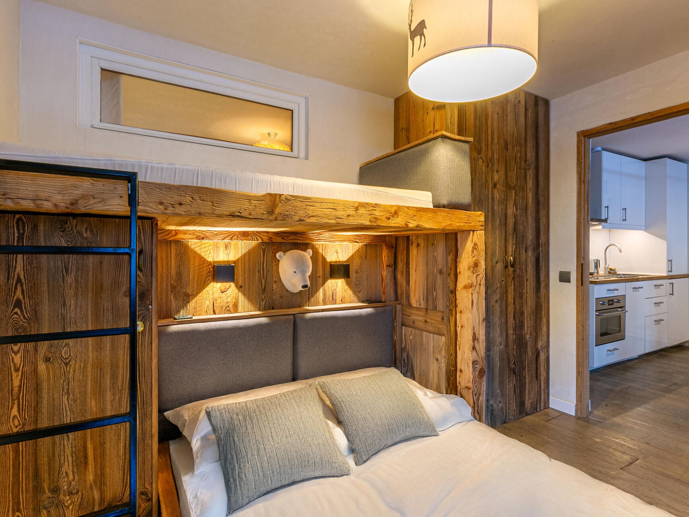 A bedroom with a wooden headboard, a bed with pillows, a bedside table, and a hanging light fixture.