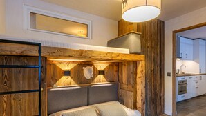 A bedroom with a wooden headboard, a bed with pillows, a bedside table, and a hanging light fixture.