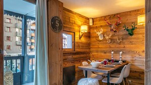 A cozy dining area with a wooden interior, a view of the outside buildings, and a clock on the wall.