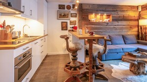 A cozy kitchen with modern appliances, a wooden dining table, and a rustic wall.