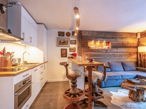 Uma cozinha acolhedora com eletrodomésticos modernos, uma mesa de jantar de madeira e uma parede rústica.