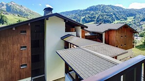 Eine Berglodge mit Holzausschau, einem geneigten Dach und Blick auf ein Tal und Berge im Hintergrund.