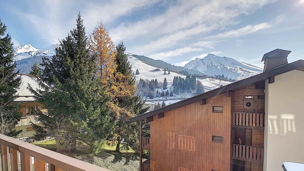 Eine Holzhütte mit einem Balkon mit Blick auf ein verschneites Gebirge.