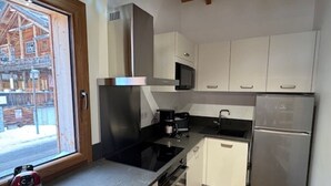 A modern kitchen with white cabinets, a stainless steel refrigerator, a microwave, and a stove.