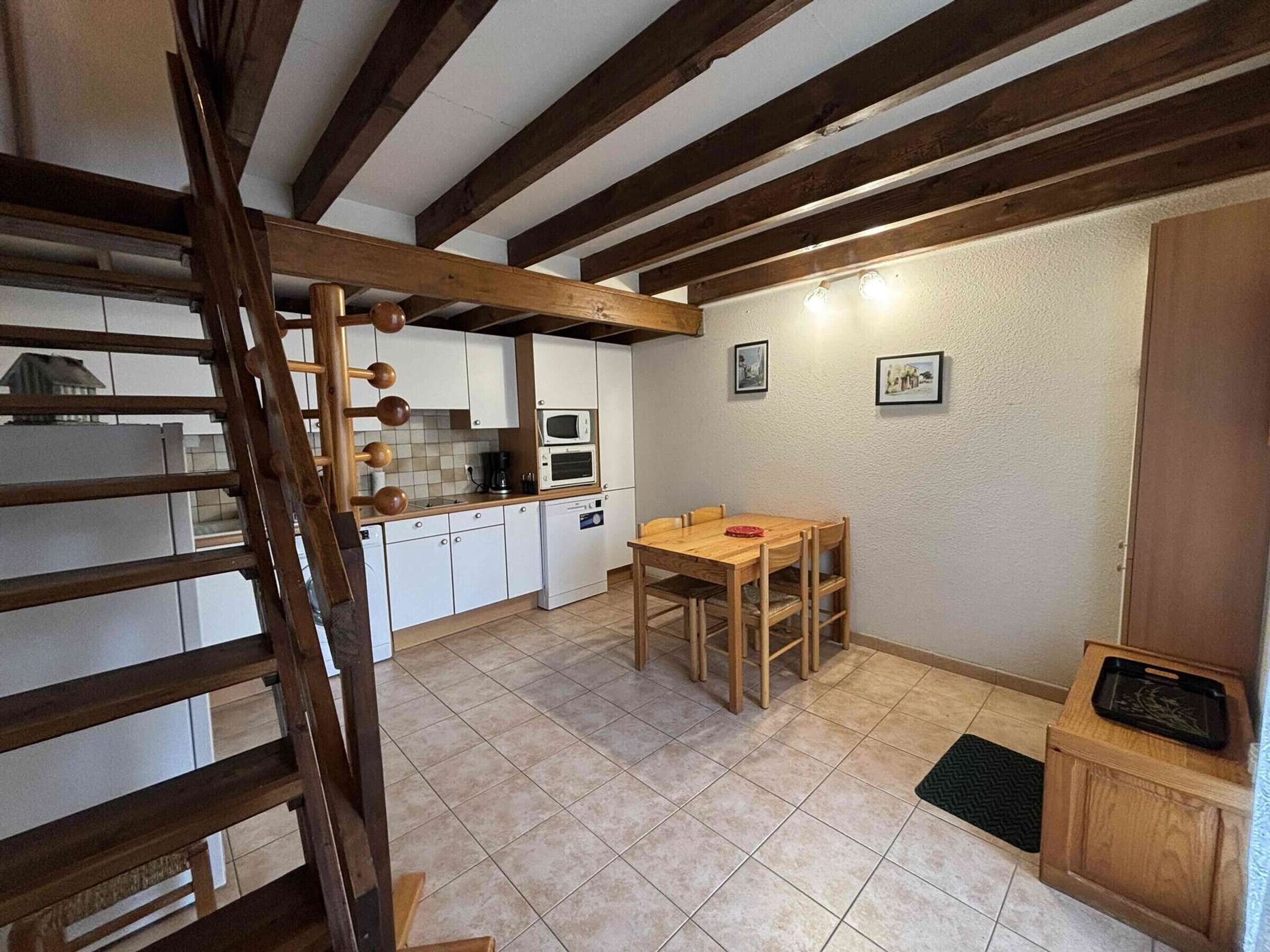 A kitchen with white cabinets, a wooden table, and a ladder.
