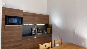 Une cuisine compacte équipée d’un four à micro-ondes, d’une machine à café et de meubles de rangement en bois.