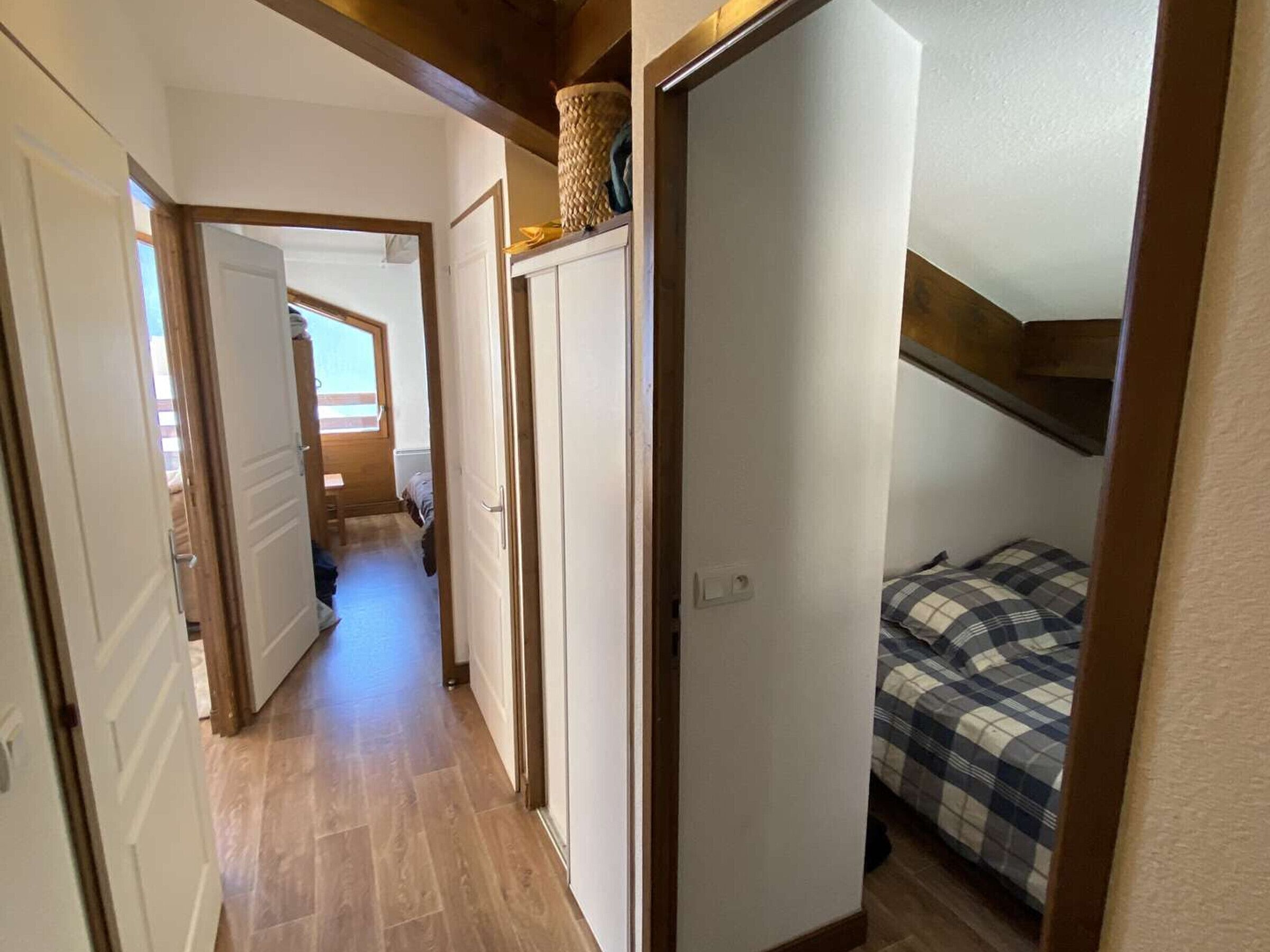 Un couloir étroit avec un lit et une armoire dans une chambre.