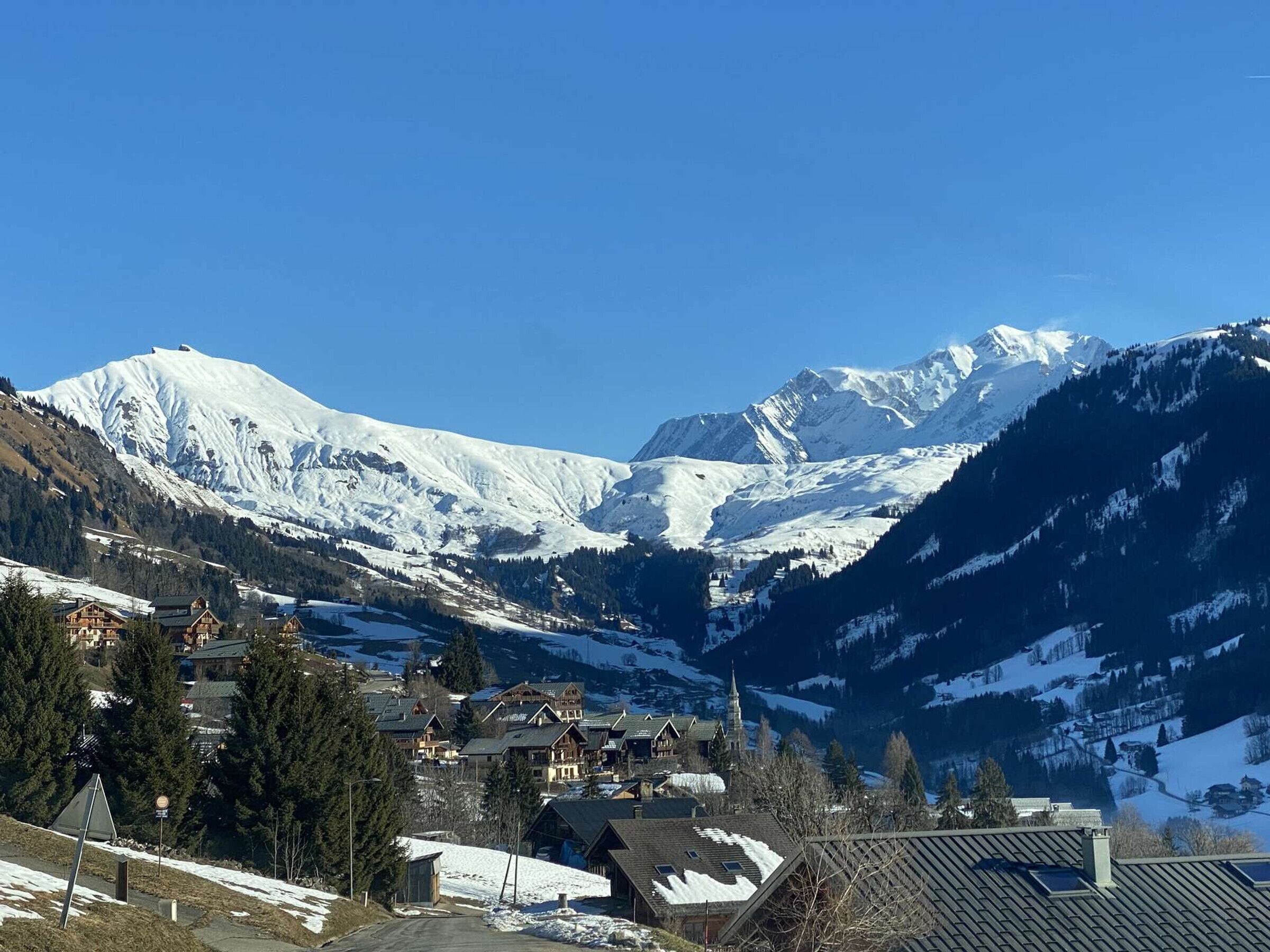 A mountain village with snow-covered peaks, wooden houses, and a church.