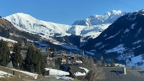 Un village de montagne aux sommets enneigés, aux maisons en bois et à l’église.