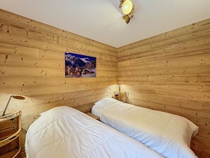 Two beds with white bedding, a nightstand, and a lamp create a cozy retreat.
