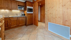 Una cocina con armarios de madera, microondas, horno y piso de baldosas.