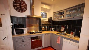 A modern kitchen with grey cabinets, a built-in oven, a microwave, and a gas stove.