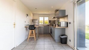 A modern kitchen with grey cabinets, stainless steel appliances, and a black trash bin.