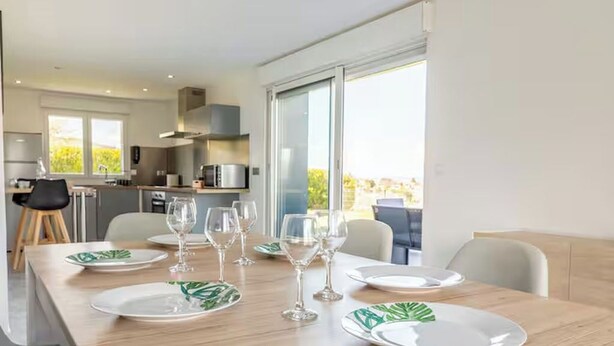 A modern kitchen with a dining area set for six.